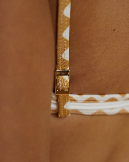 Focus sur le dos du haut de bikini Cap Ferrat porté par une femme blonde – détail de l’ajustable et des bretelles fines avec finitions dorées. Haut vendu séparément.